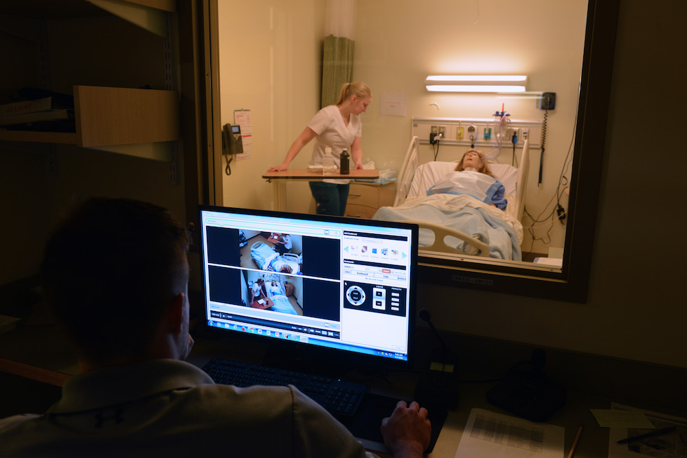 A computer monitors a female nursing 快播成人 working with an adult patient simulation